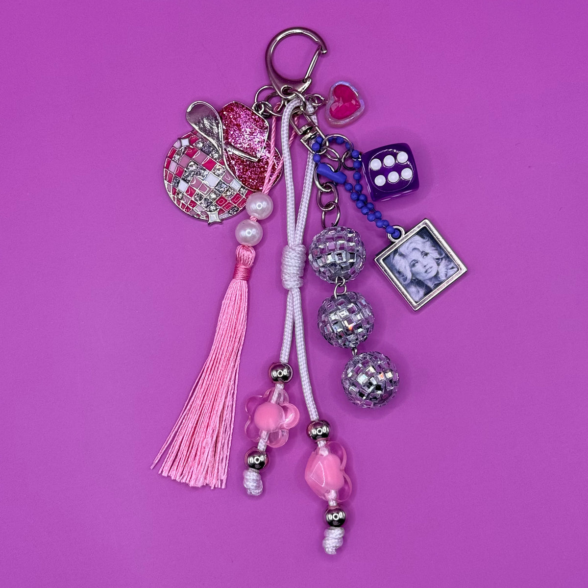 1-of-1 handmade Dolly trinket bag charm with an enamel disco ball charm topped with a glitter pink cowboy hat, mirrored disco ball beads, a purple lucky die, pink tassel and framed portrait charm.