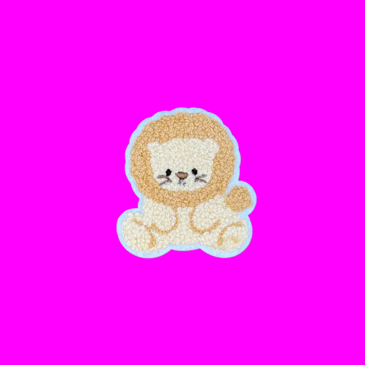 A small chenille embroidered lion patch or applique with a cream face and body, a tan/golden mane.