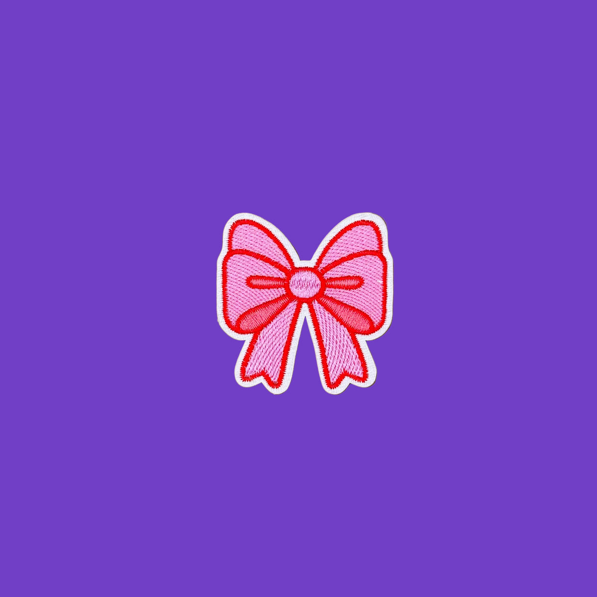 A pink embroidered bow patch with a white border, centered on a smooth purple background.