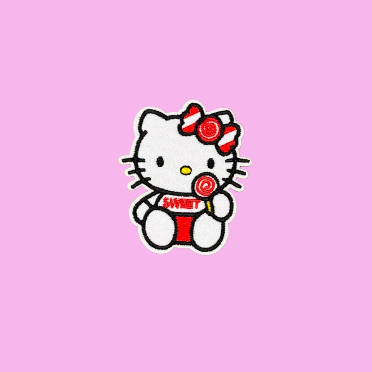 Hello Kitty with lollipop and sweet written on her white teeshirt embroidered patch on a pink background