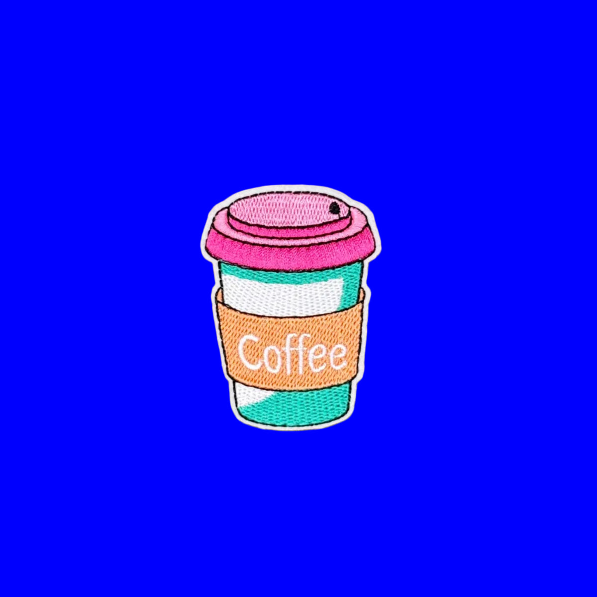An embroidered patch of a takeaway coffee cup with a pink lid, teal body, and orange sleeve labeled 'Coffee', shown on a plain brown background.