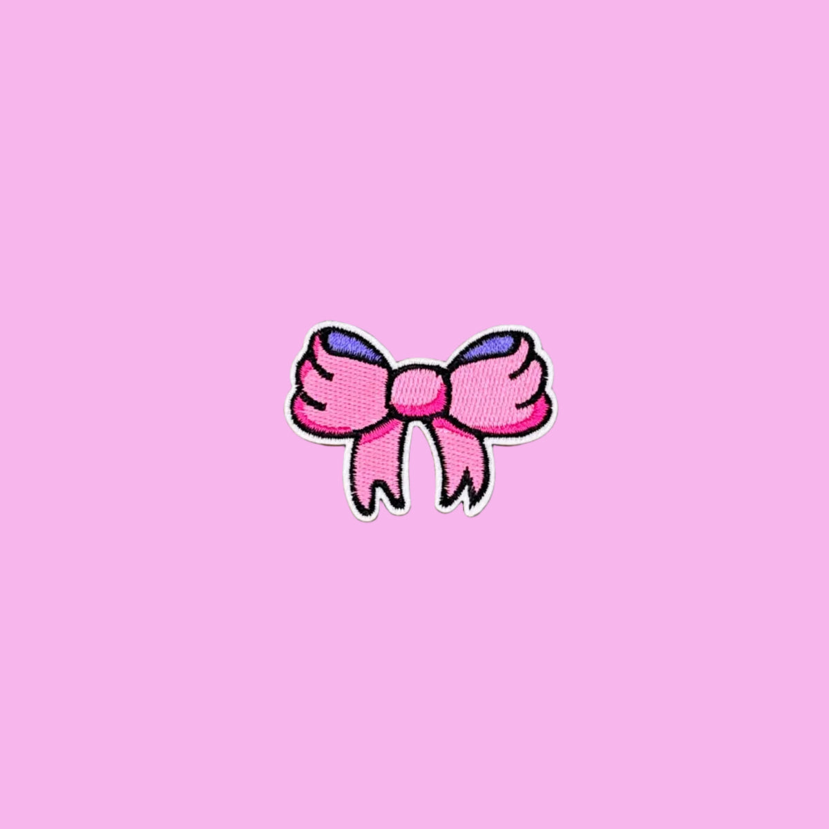 Small cartoon girly bow patch with pink and purple ribbon and a black outline embroidered iron on patch.