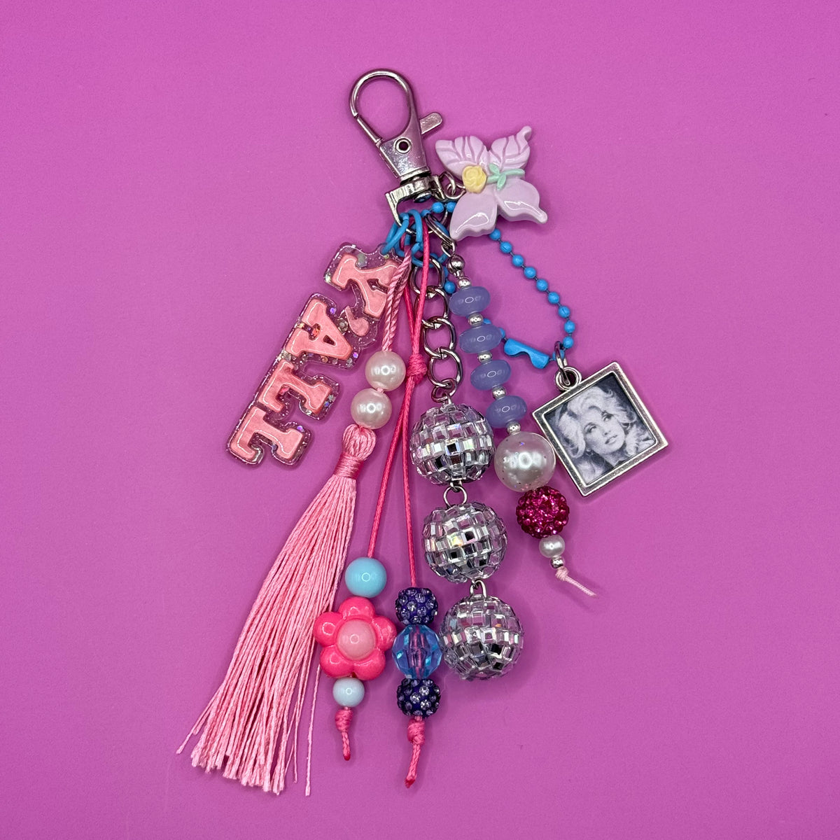 1-of-1 handmade Dolly trinket bag charm with a glittery pink Y'ALL charm, three mirrored disco ball beads, a pink tassel, pastel lily charm and framed portrait charm on a silver clasp.