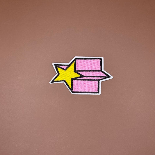 Yellow shooting star iron-on patch cutting across a pink trail outlined in black