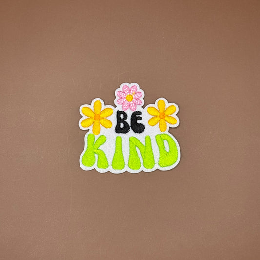 Be Kind iron-on patch in black and lime bubble letters framed by yellow and pink daisies
