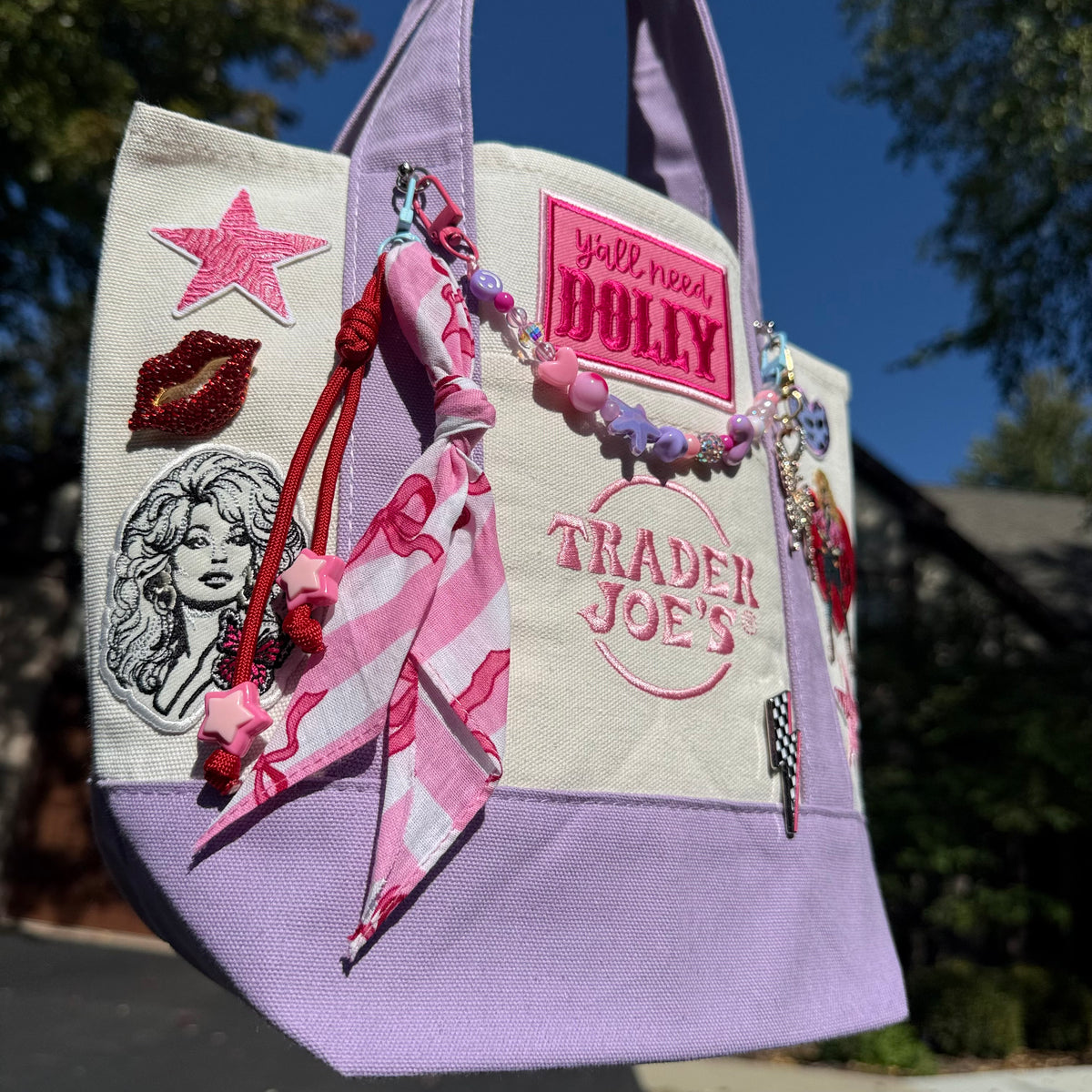 Dolly Parton Pretty in Pastel mini tote by PrettyMUCH, a lavender and cream Trader Joe's canvas tote with Dolly patches and charms.