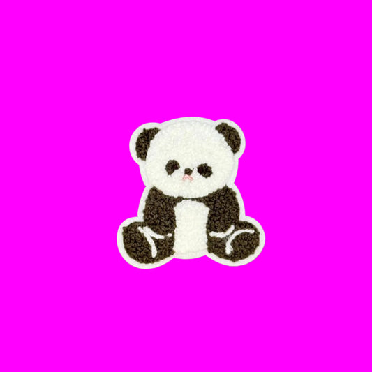 A small embroidered panda patch with a white body and black ears, eyes, and limbs, centered on a smooth brown background.