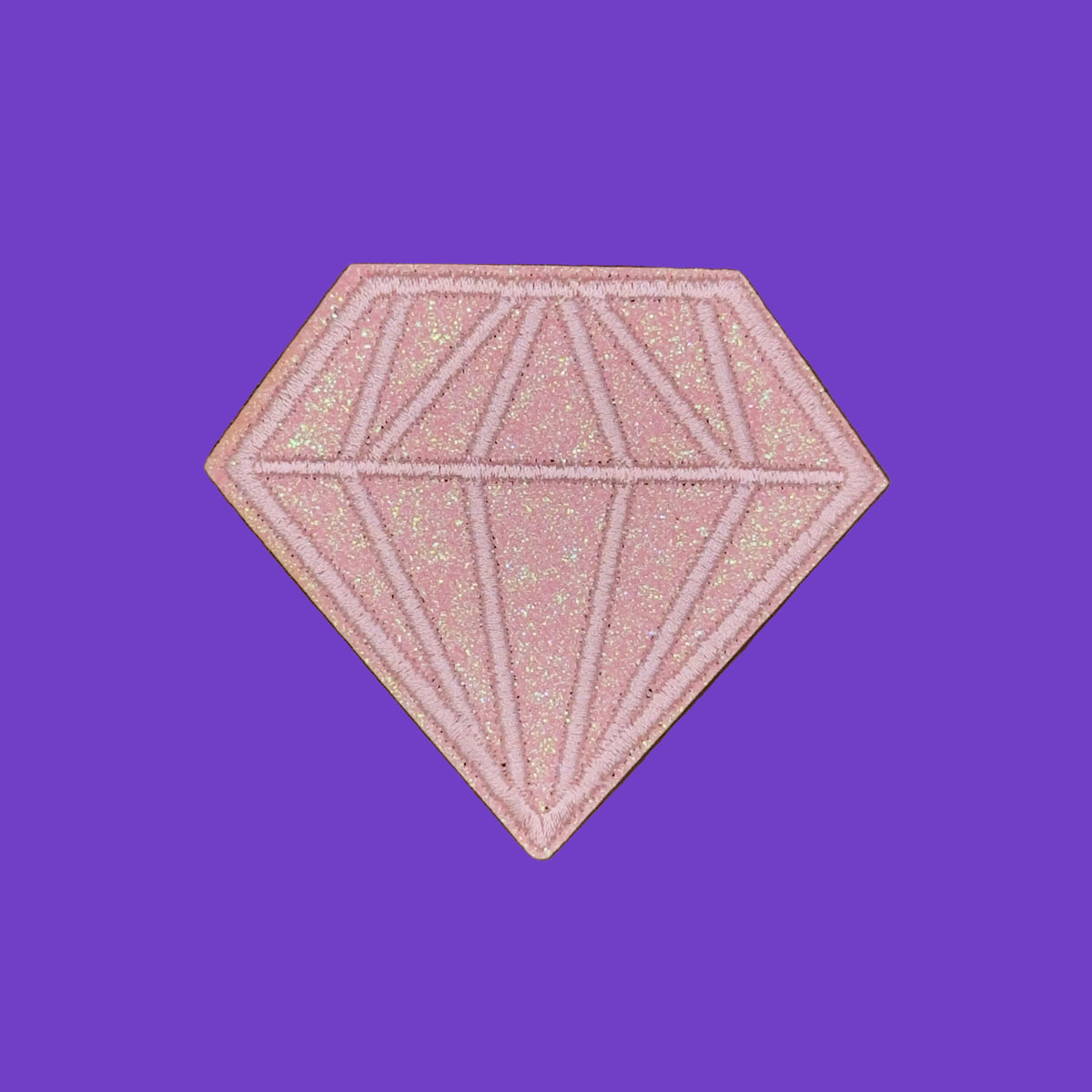 A pink diamond-shaped glittery cosmetic compact or powder pan with geometric line detailing, shown on a solid brown background.