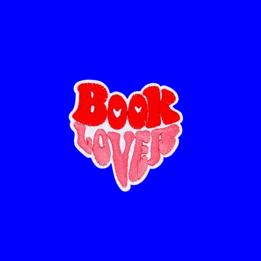 Book lover iron-on patch with red and pink bubble letters stacked into a heart shape