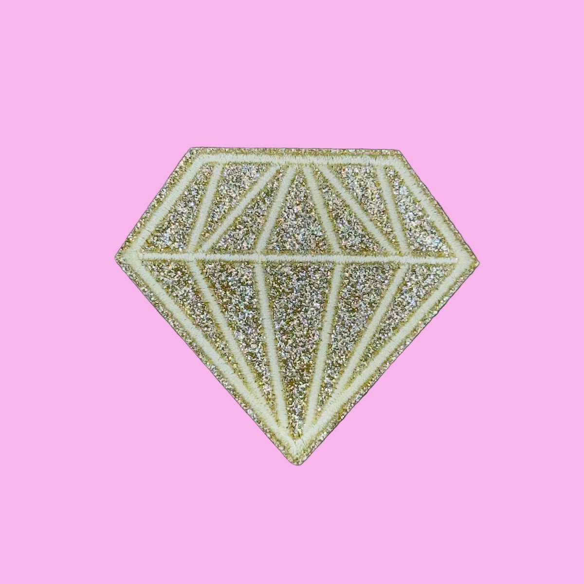 A glittery diamond-shaped patch with a faceted gemstone design, featuring a pale gold glitter background and cream-colored outlines, set against a solid purple background.