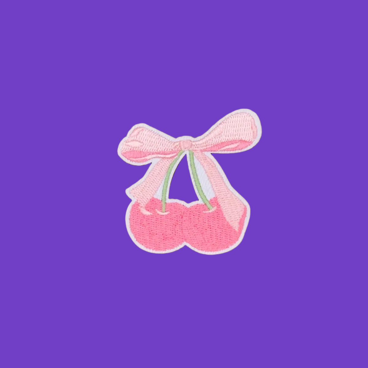 Embroidered, iron-on patch featuring a coquette-themed pair of pink cherries tied at the top of the stems with a soft pink bow.