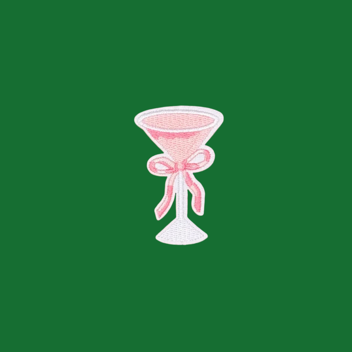 An embroidered patch of a pink cocktail glass tied with a pink ribbon.