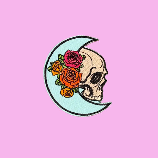 Pale blue crescent moon iron-on patch cradling a skull in profile with roses