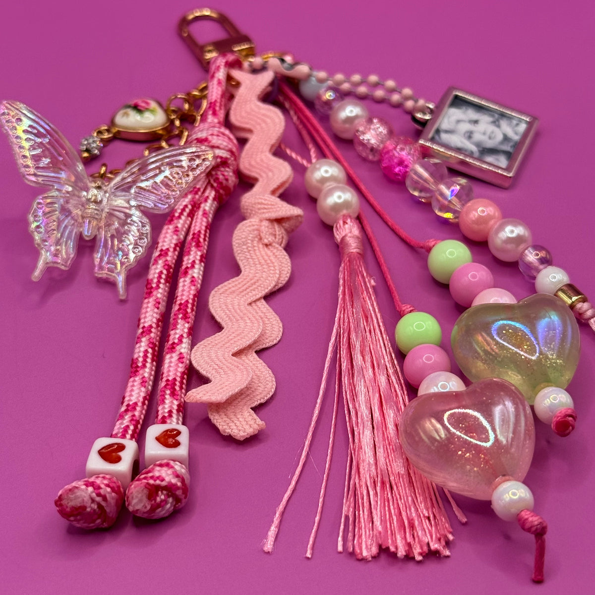 Detail of the 1-of-1 Butterfly Ric-Rac Dolly bag charm by PrettyMUCH, with glitter heart beads, pearls and a silky pink tassel.