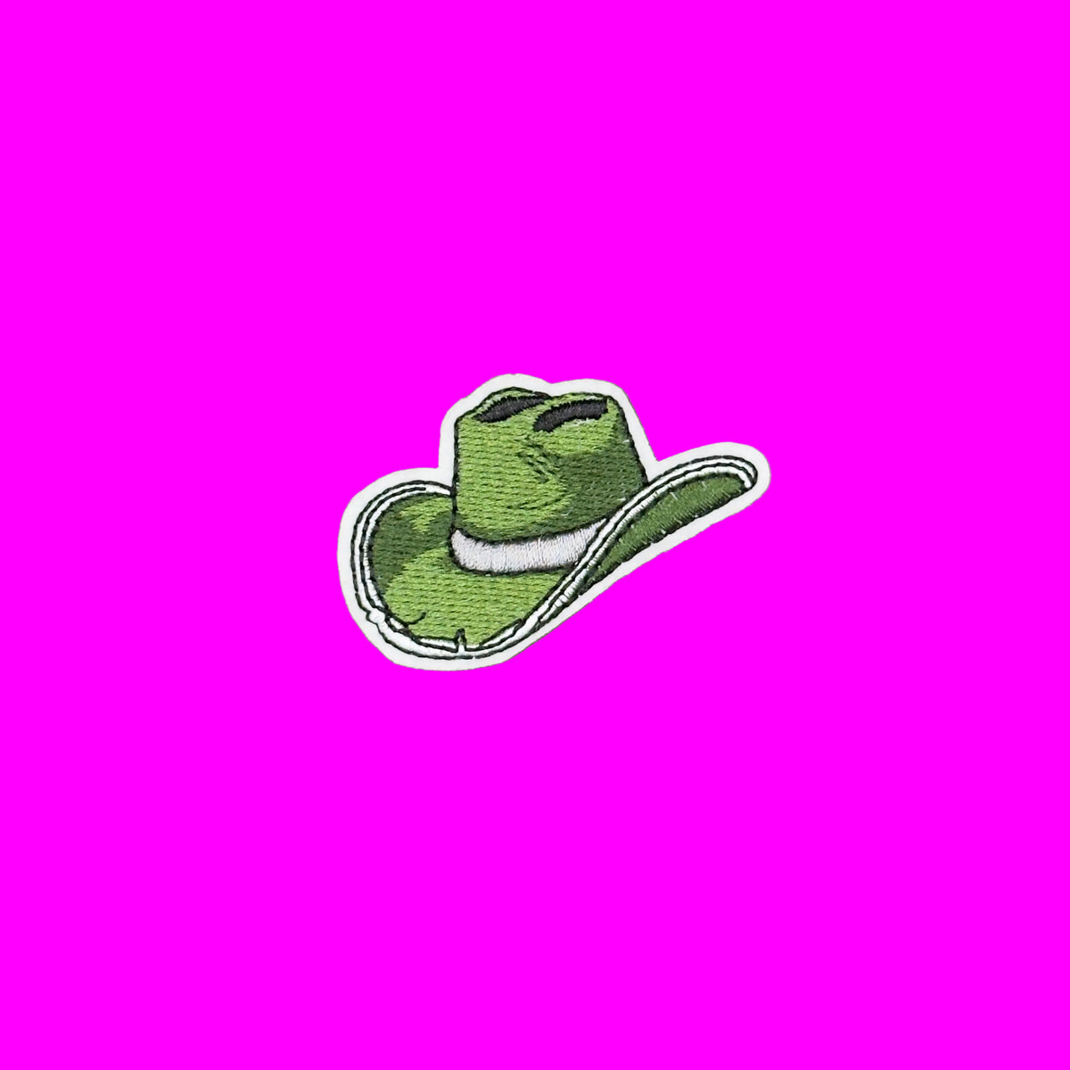 An embroidered patch of a green cowboy hat with a white band and white border, shown on a solid brown background.
