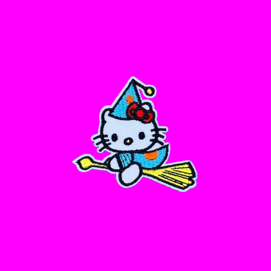 An embroidered patch of Hello Kitty dressed as a witch, riding a broomstick against a solid blue background.