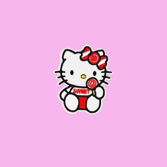 Hello Kitty with lollipop and sweet written on her white teeshirt embroidered patch on a pink background