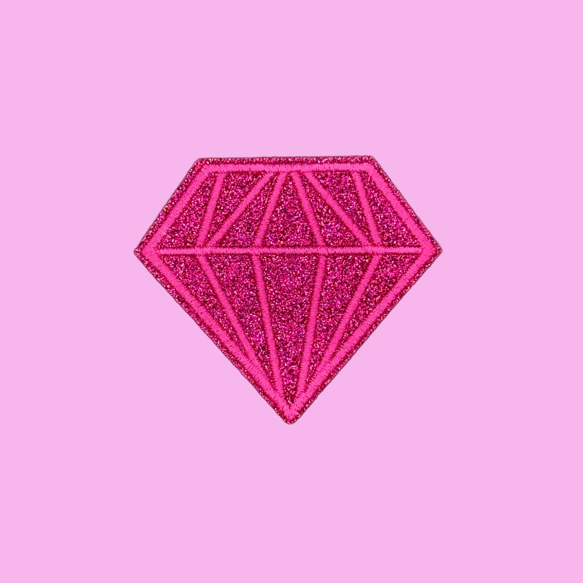A bright pink glitter diamond-shaped patch with geometric line details, centered on a solid pale pink background.