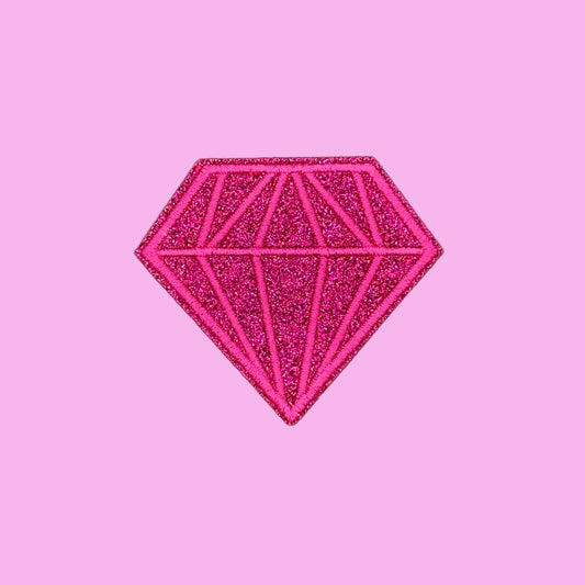 A bright pink glitter diamond-shaped patch with geometric line details, centered on a solid pale pink background.