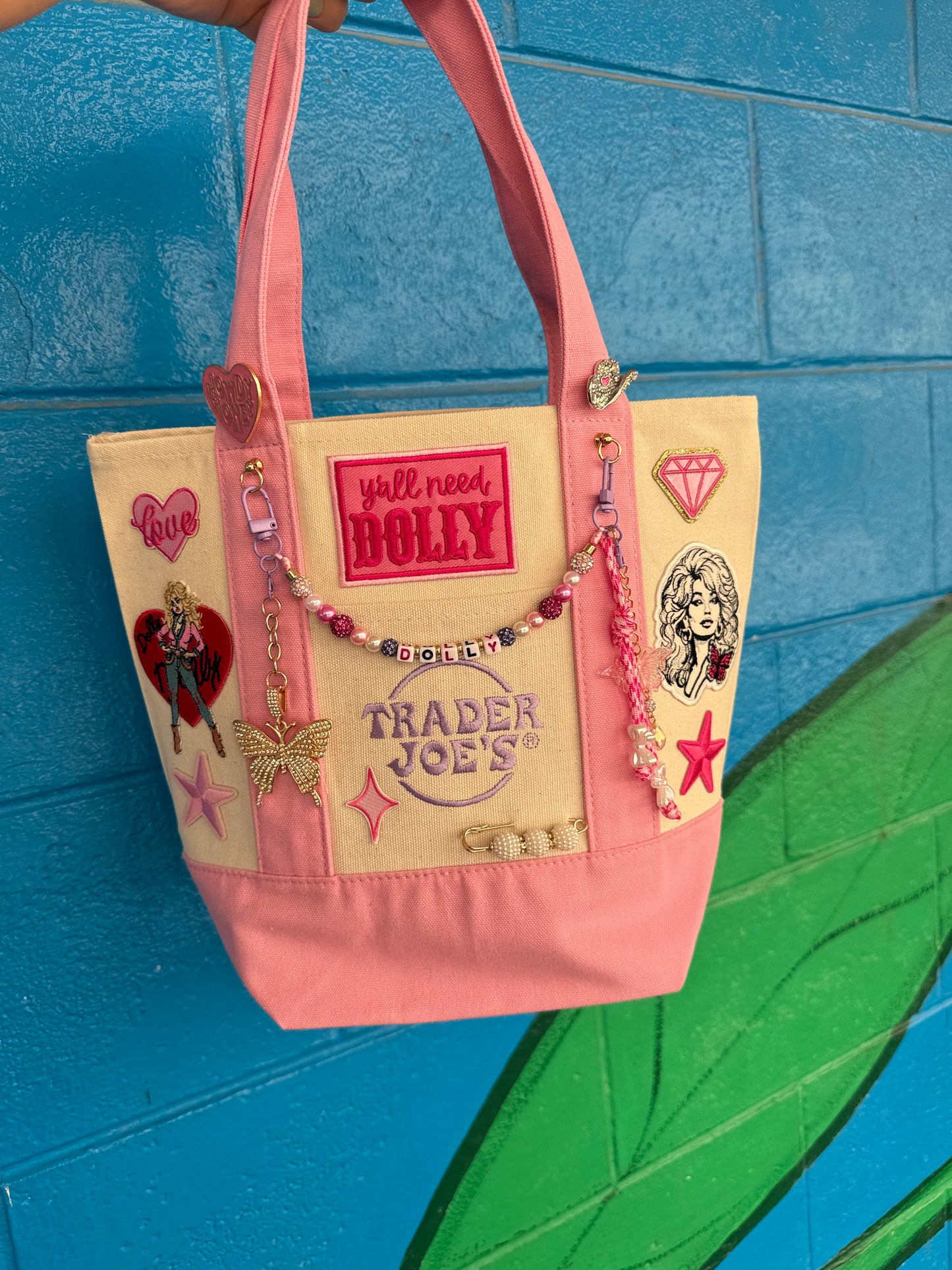 Pink tote bag decorated with Y'all Need Dolly patch and Dolly Parton patches