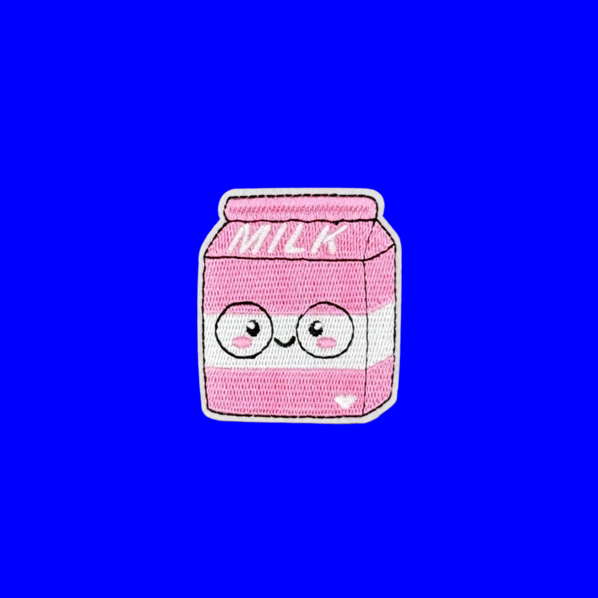 A pink embroidered patch shaped like a milk carton with a cute cartoon face, shown on a solid blue background.