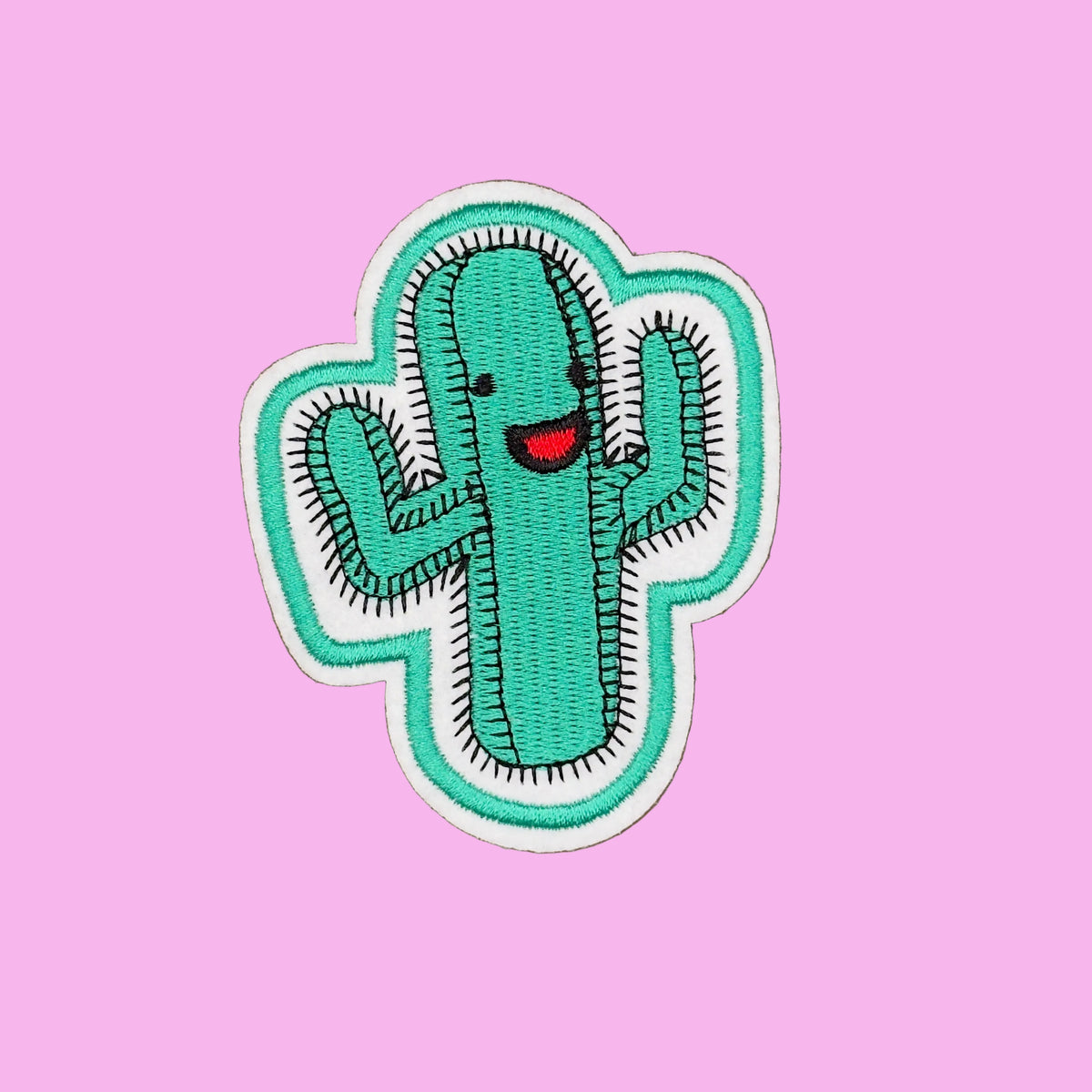 An embroidered patch of a smiling green cactus with a red mouth and black spines, set against a solid brown background.