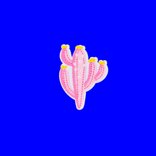 A pink embroidered cactus patch with small yellow flowers and a white border, displayed on a solid brown background.