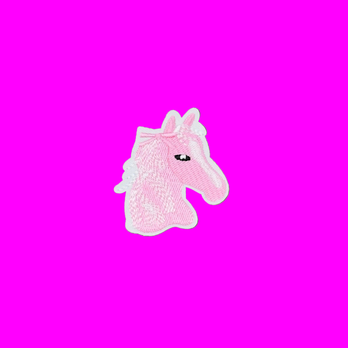 A pink embroidered horse head patch with a white border.