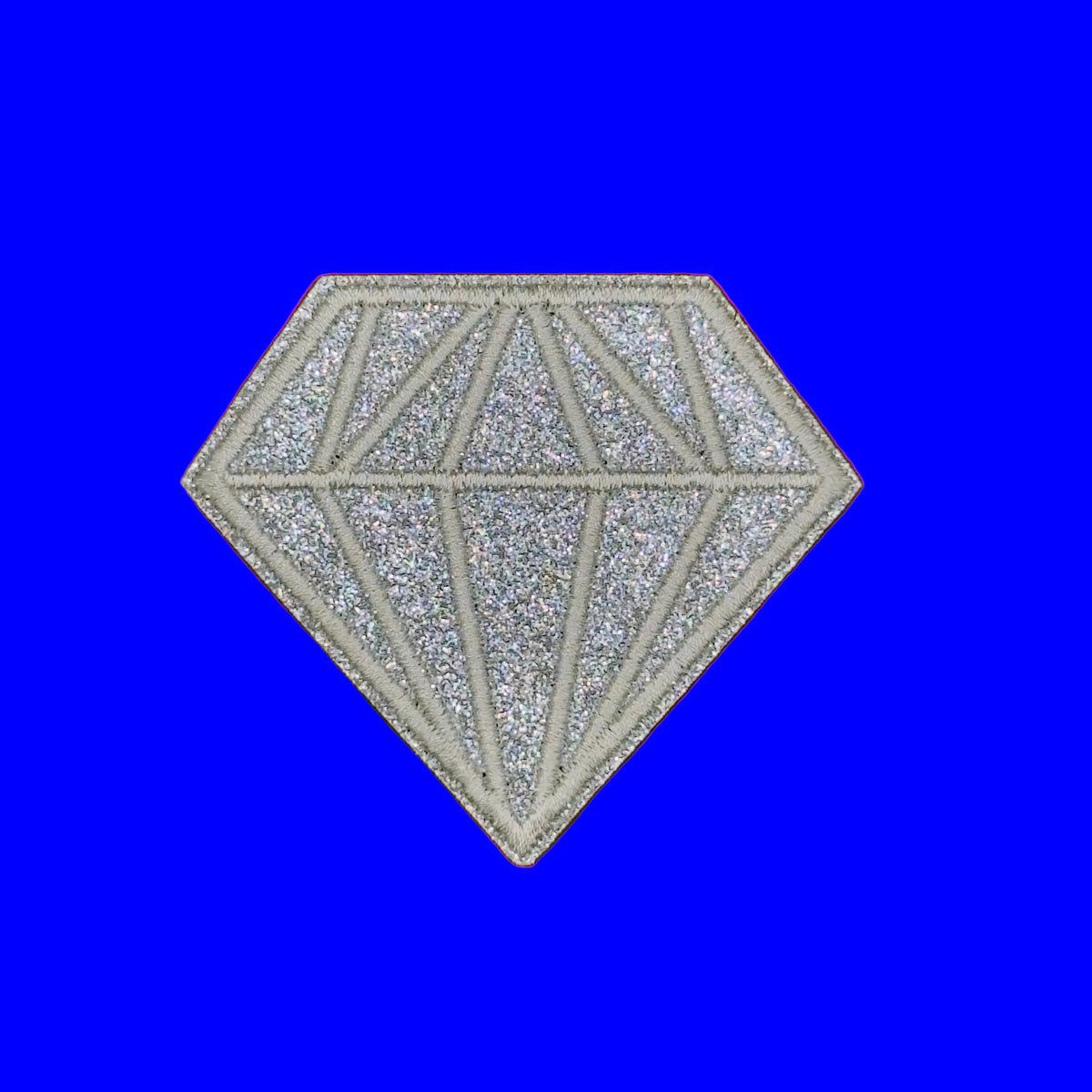 A glittery silver diamond-shaped patch with geometric line details, displayed on a solid brown background.