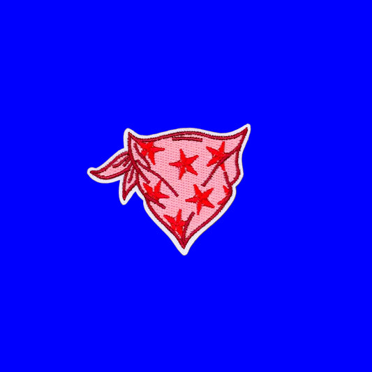An embroidered patch of a pink bandana with red stars and a white border, displayed on a solid blue background.