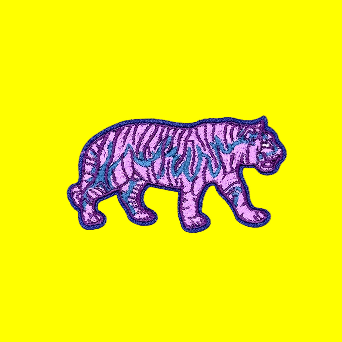 A purple embroidered tiger patch with black stripes and blue accents, shown on a solid brown background.