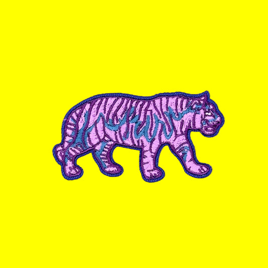 A purple embroidered tiger patch with black stripes and blue accents, shown on a solid brown background.