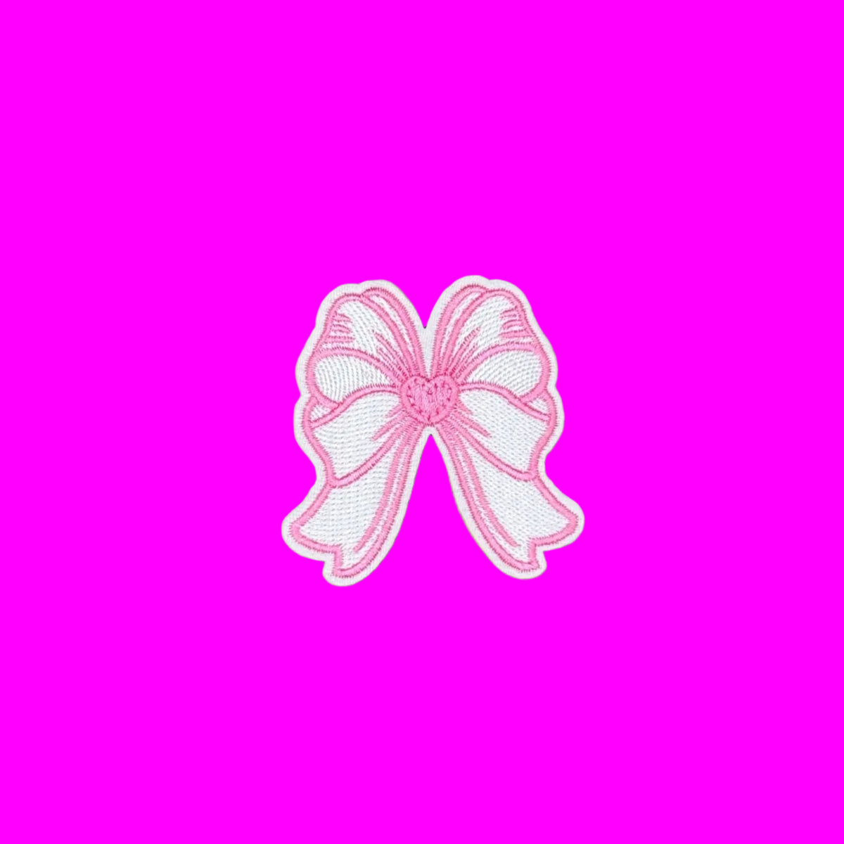 A pink and white embroidered bow patch with a white border, centered on a solid brown background.