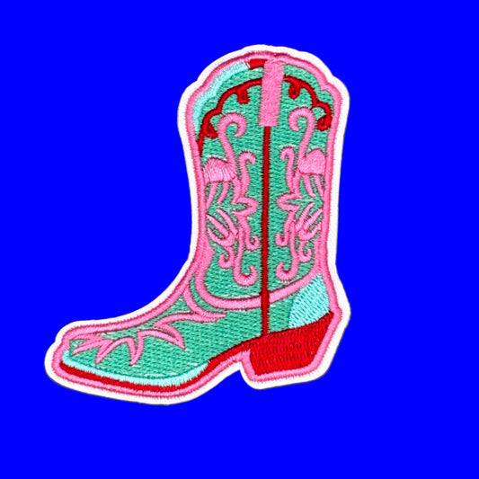 Embroidered cowboy boot patch in mint green, pink, and red on a solid purple background.