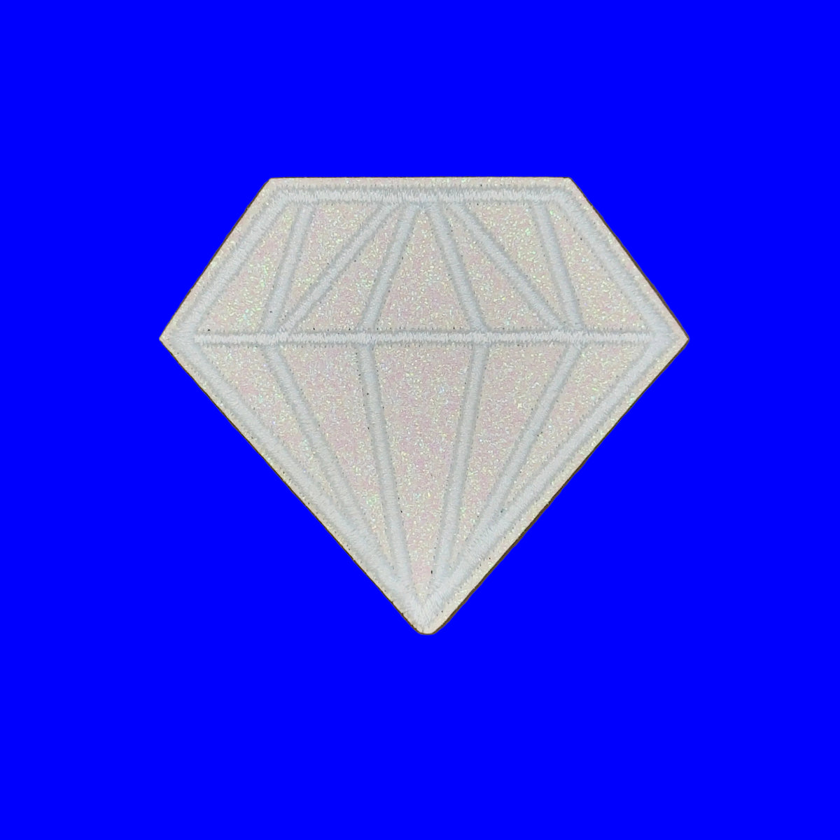 A white diamond-shaped patch with a faceted gemstone design, shown on a solid brown background.