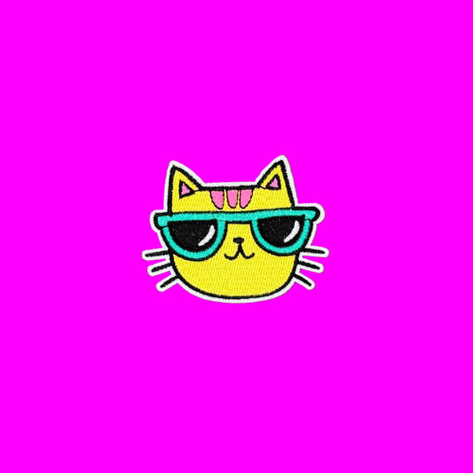 Yellow cool cat with pink stripes and teal colored sunglasses and black whiskers embroidered iron-on patch.
