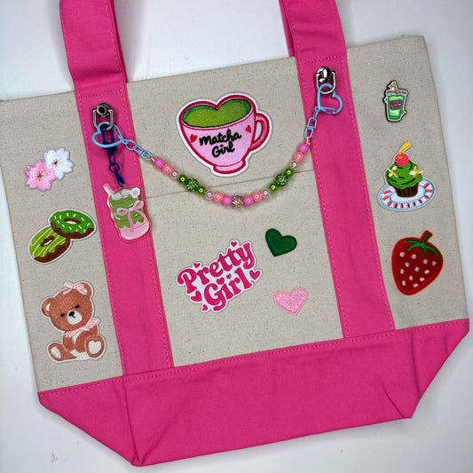 Official Matcha Fest tote in pink with matcha patches, pins and beaded bag chain